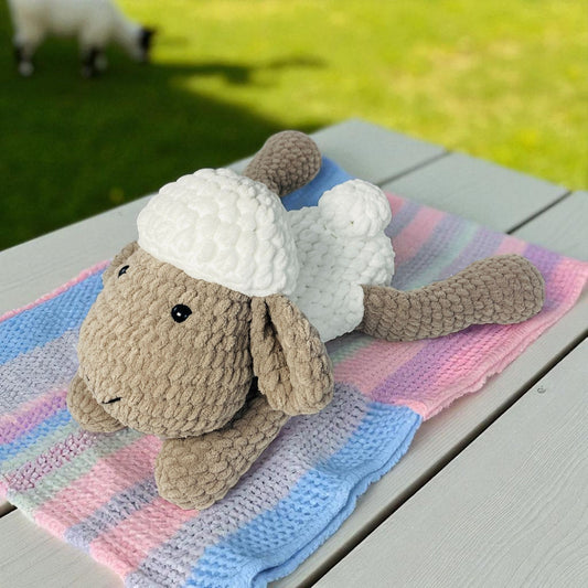 hand Knitted sheep toy on a colorful blanket with a grassy background