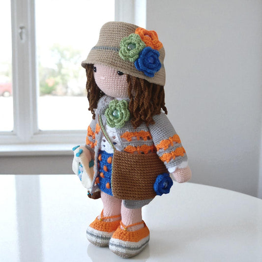 Crocheted doll with a colorful hat and outfit on a white surface.