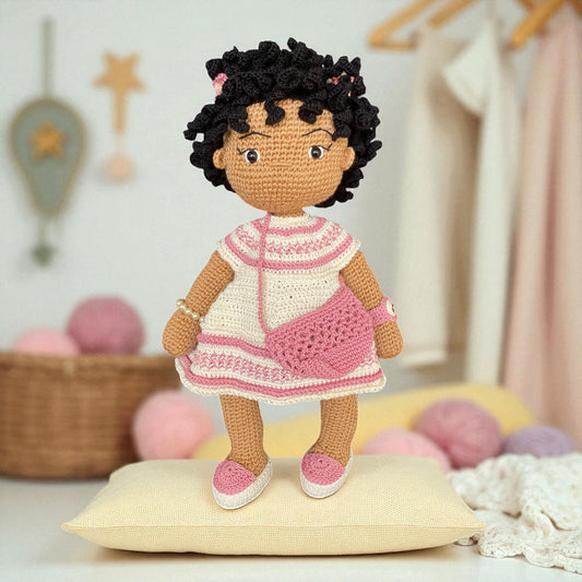 Crocheted doll with a pink dress in a cozy room setting