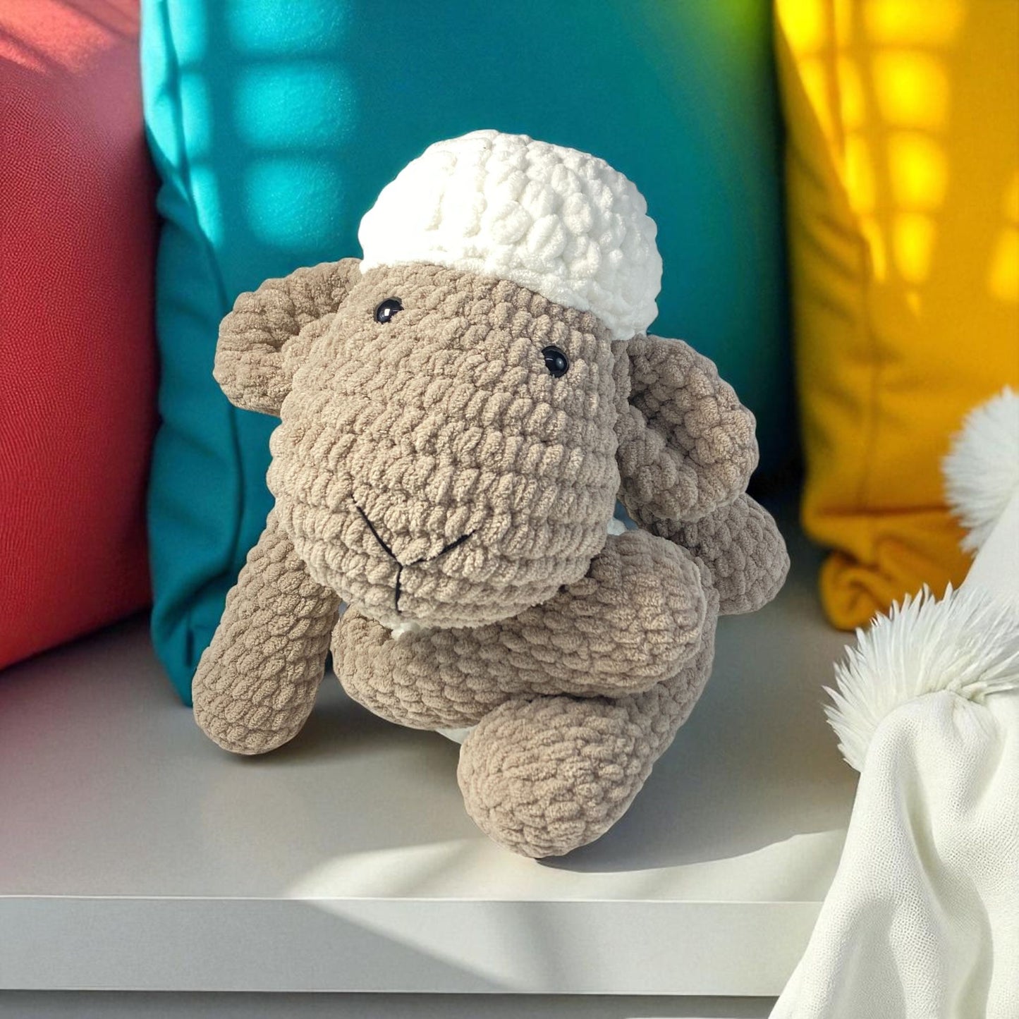 knitted sheep sitting cross legged on couch with head resting on leg 