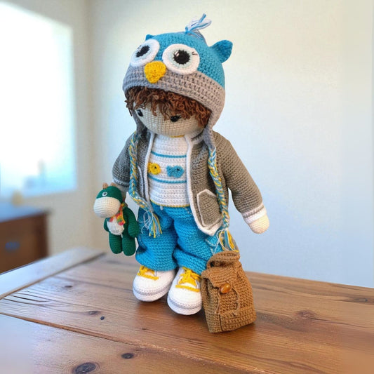 handmade boy doll wearing hand crochet owl cap ,grey jacket carrying a toy and a brown backpack 